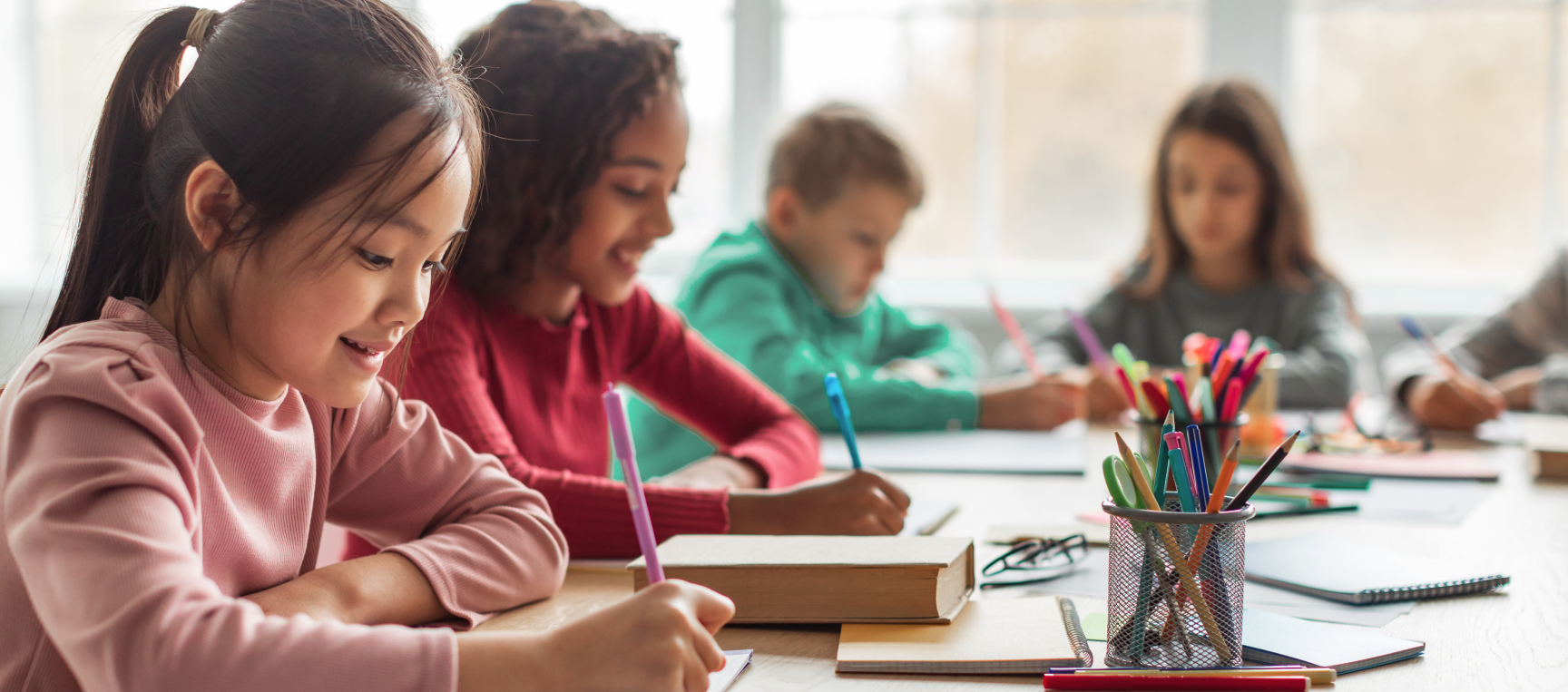 Children sitting at a desk and writing.